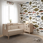 Nursery room with wooden crib and dresser against a wall with fish-themed wallpaper.