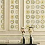Decorative wall with sunburst pattern and two wooden figures on a table.