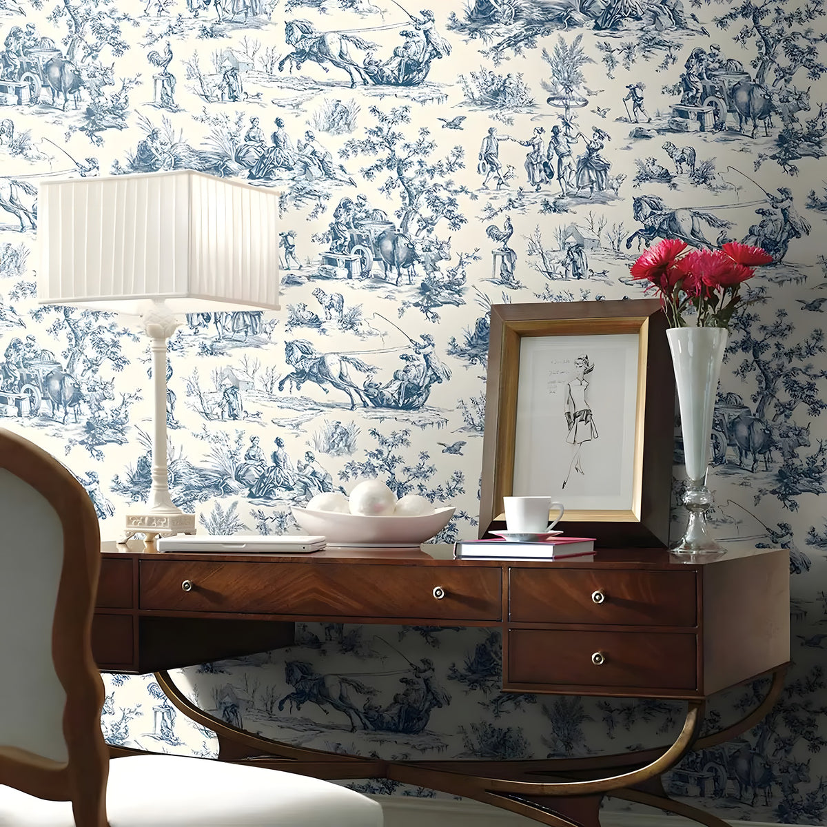 Decorative room with blue and white toile wallpaper, wooden desk, lamp, and vase.
