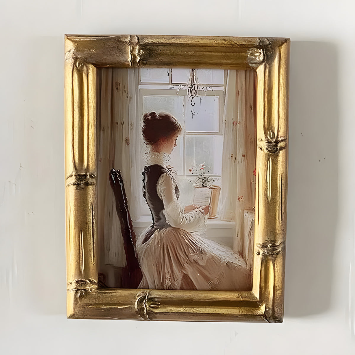 Framed artwork of a woman sitting by a window with a gold frame.
