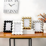 Decorative photo frames on a wooden surface with a clock above