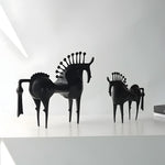 Black horse-shaped chairs on a white surface with a white background