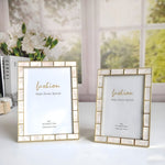 Two gold-framed picture displays on a surface with a blurred floral background