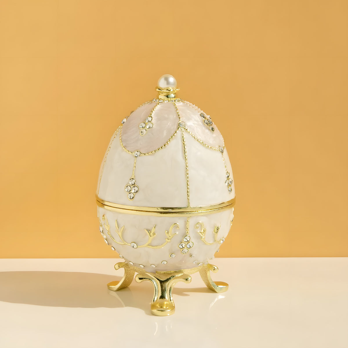 Decorative egg with gold accents and pearls on a beige background