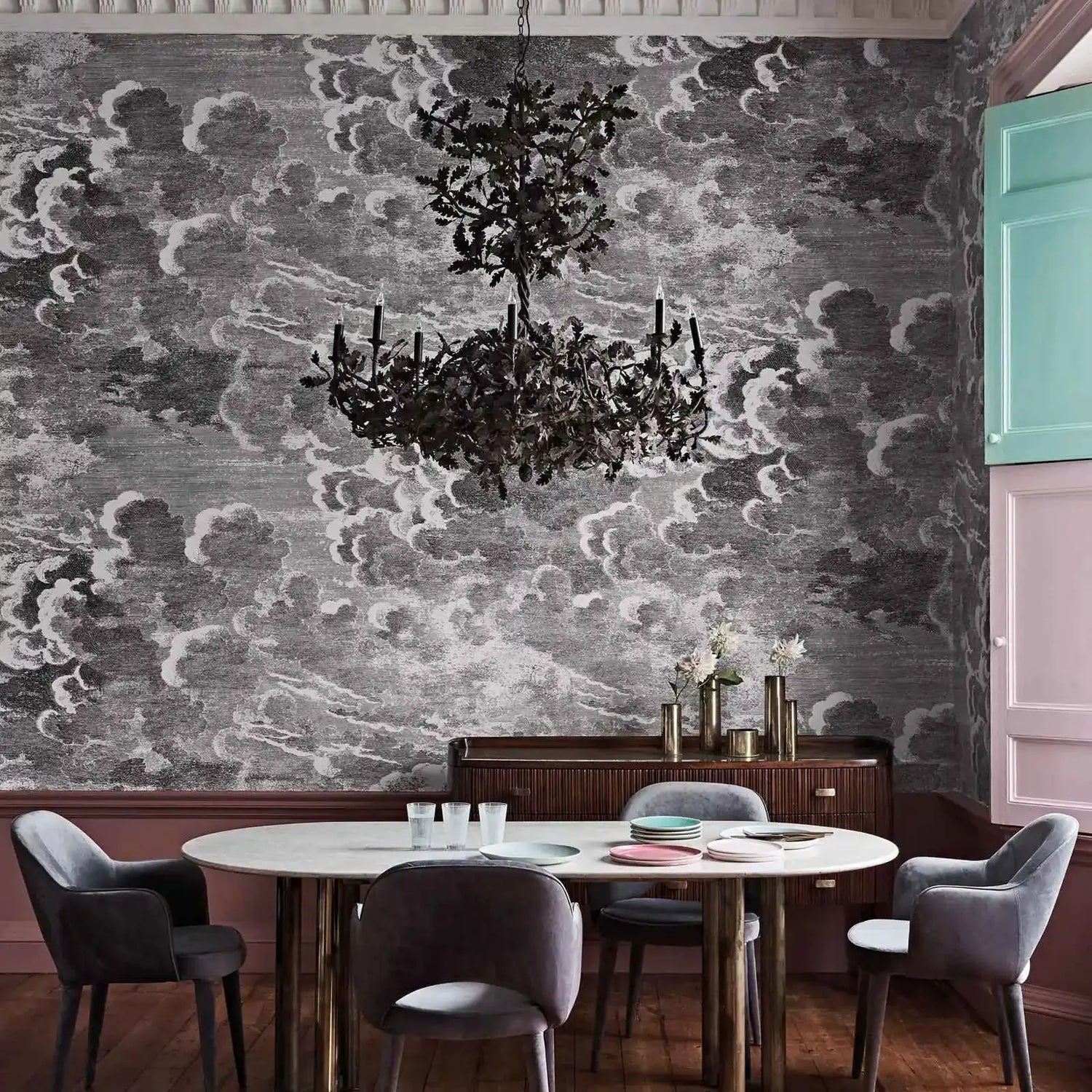 Dining room with a chandelier, table, and chairs against a patterned wall.