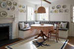 Nautical-themed dining room with a fireplace, bench seating, a rug, and decorative plates on the wall.