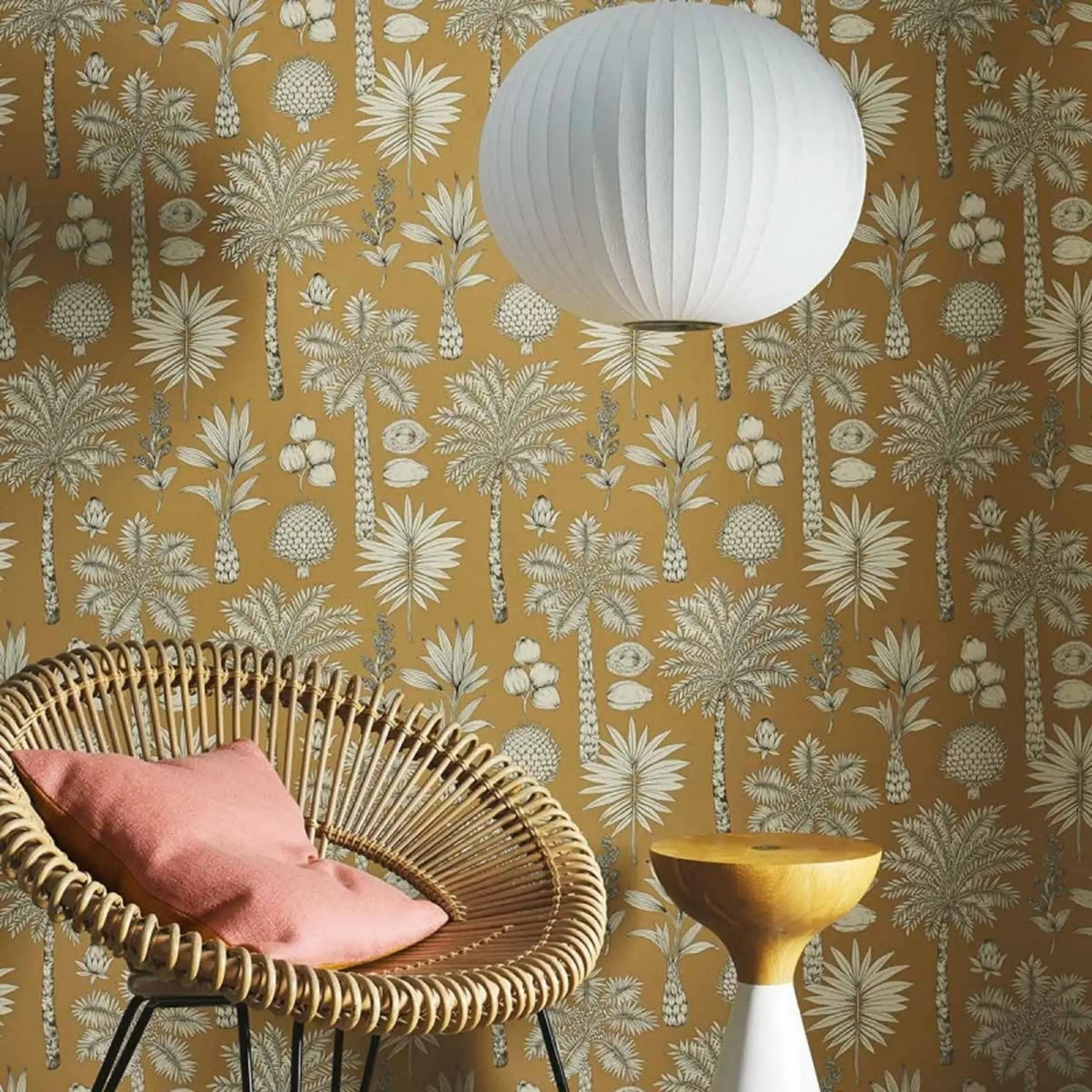 Wicker chair with a pink cushion against a patterned wall with palm trees.