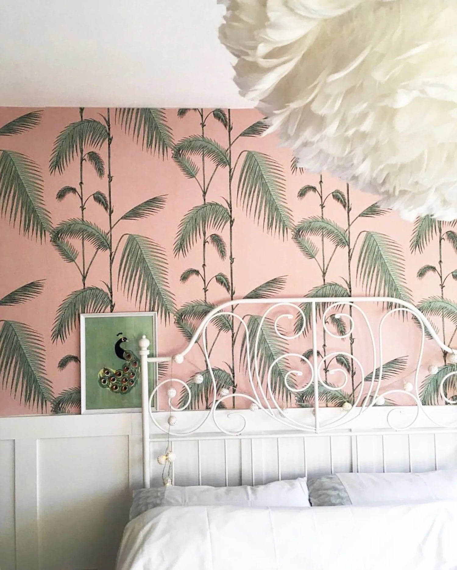 Bedroom with pink palm leaf wallpaper and white headboard