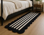 Black and white striped rug on a wooden floor in a bedroom setting.