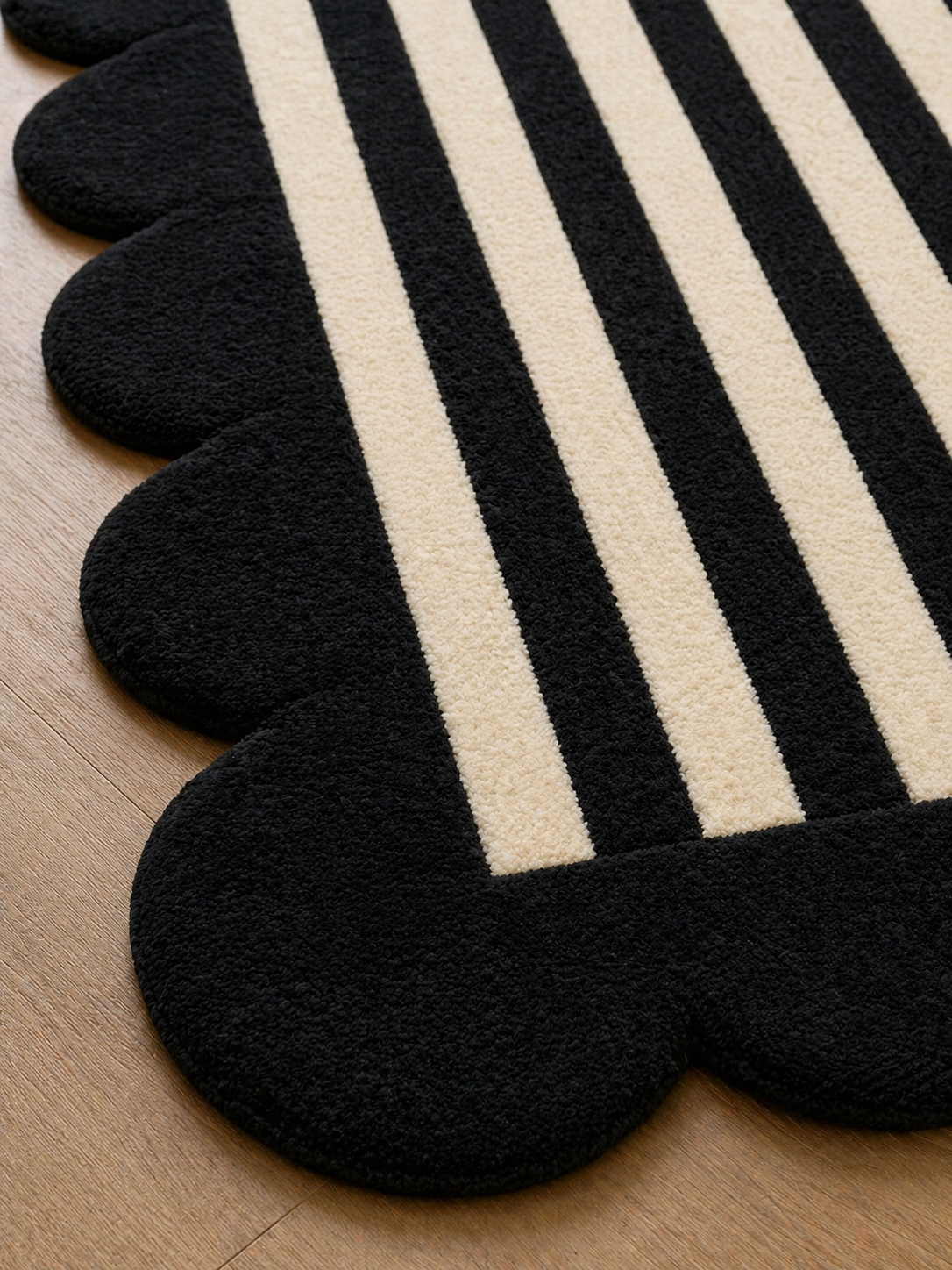 Black and white striped rug with scalloped edges on a wooden floor