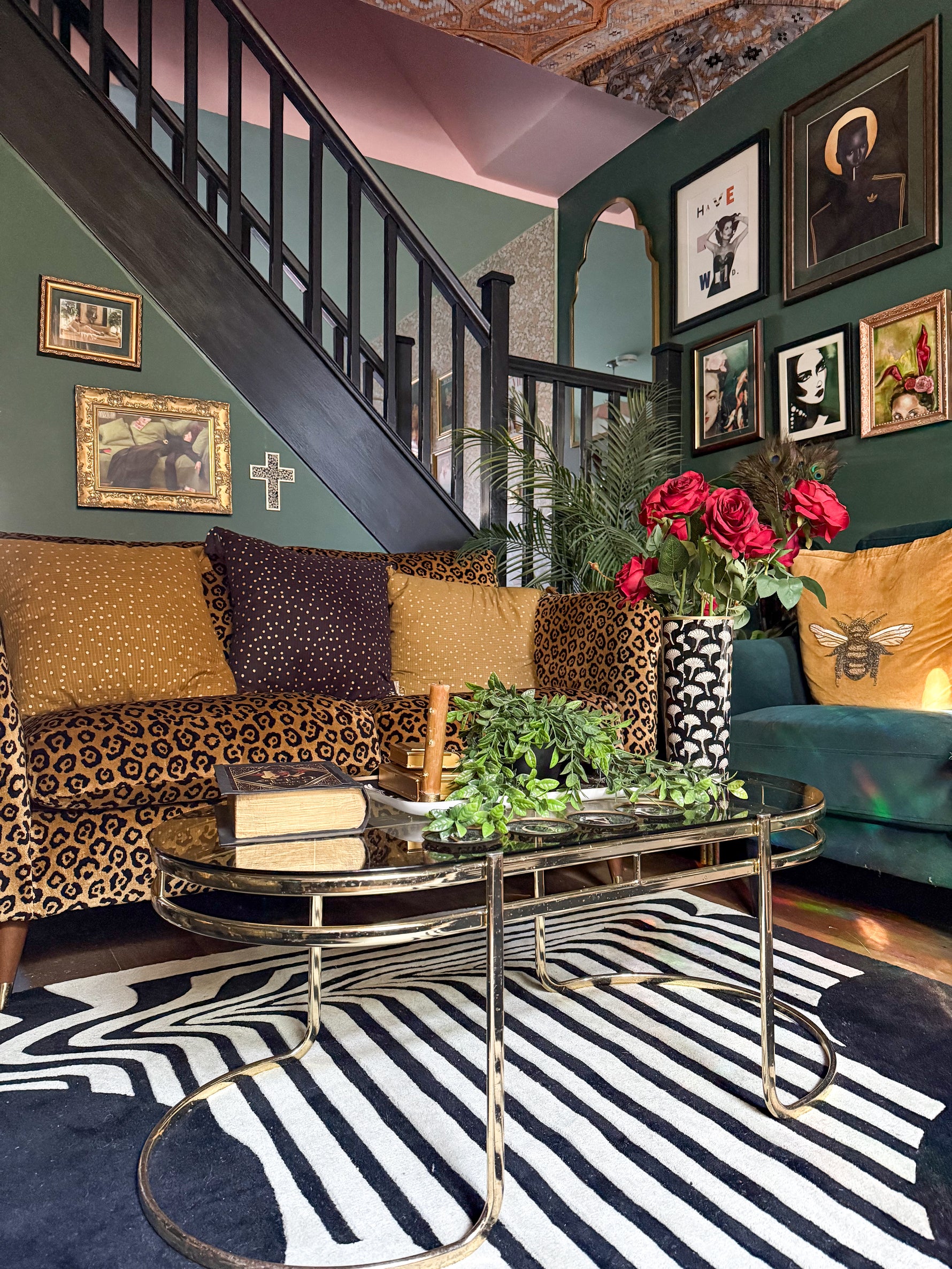 Living room with colorful decor, including a staircase, framed pictures, art deco black and white rug, and a coffee table.