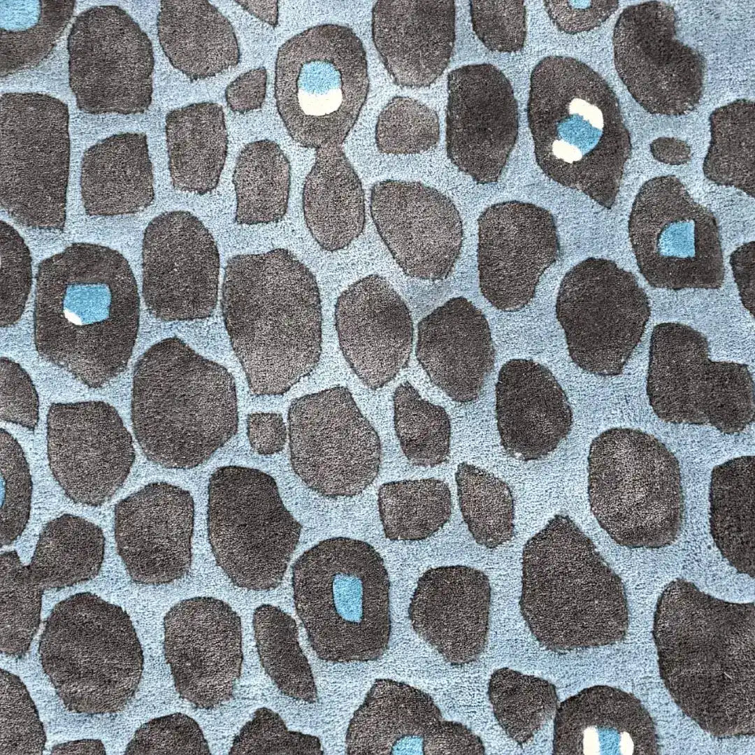 This image showcases a vibrant Blue and Black Leopard Print Hand Tufted Wool Rug. The abstract pattern features bold black spots against a soothing blue background, making it an ideal choice for bedroom rugs or large area rugs for living room spaces. The wool rug's unique design adds a modern touch to any room, combining style with comfort.
