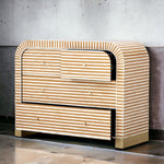 A modern three-drawer dresser with a curved top and bottom, covered in light natural wood and white horizontal stripes, set against a gray concrete wall.