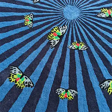 Vibrant hand tufted wool area rug featuring colorful butterflies over a striking blue and black radial design. Ideal for adding flair to bedrooms or as a large area rug in living rooms.