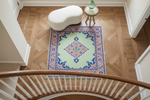 Decorative rug with a geometric pattern on a wooden floor, viewed from above.