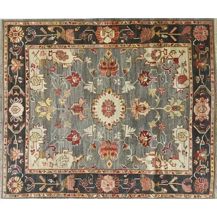 This image showcases a charming floral cascade hand-knotted area rug with intricate patterns. The rug features a harmonious blend of earthy tones, including deep reds and soft grays, creating a vintage and elegant look. Perfect for adding a touch of sophistication to any room.