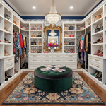 Luxurious walk-in closet with white shelves, a blue traditional floral wool rug, clothing, and decorative elements.