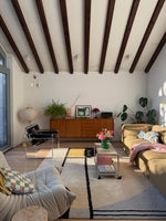 Modern living room with contemporary rug, wooden beams, furniture, and decorative elements.