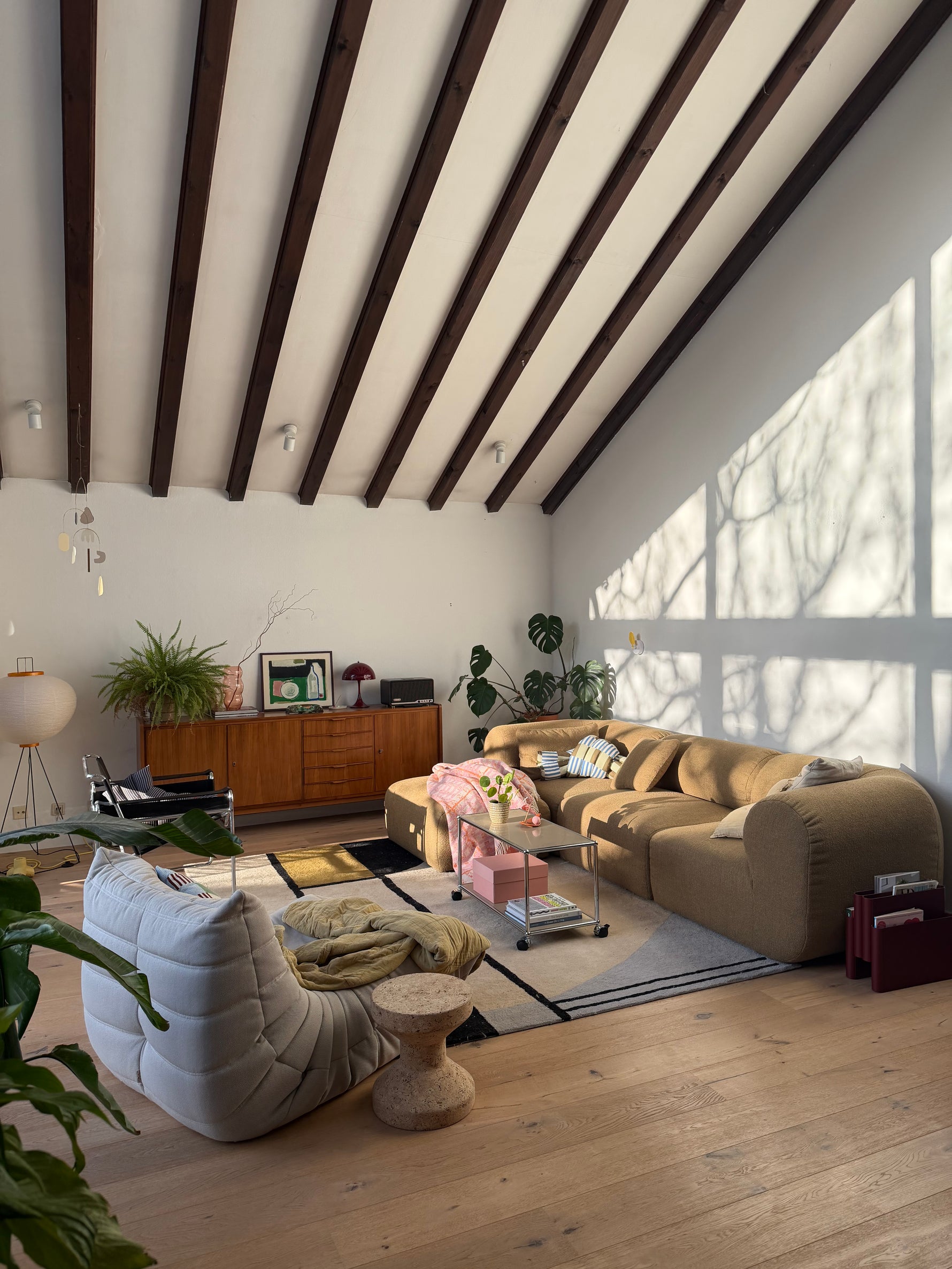 Modern living room with contemporary rug, wooden floor, sofa, and decorative elements.
