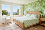 Bedroom with wooden bed, pine apple rug, floral bedding, and green wall paper.