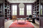 Living room with bookshelves, a coffee table, and a colorful rug.