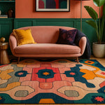 A vibrant hand-tufted area rug with abstract geometric patterns in shades of red, blue, and yellow. This large wool rug is perfect for a living room setting, complementing the cozy pink sofa and green panelled walls for a contemporary look.