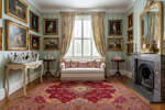 Luxurious living room with classical decor, including a fireplace, sofa, and framed artworks.
