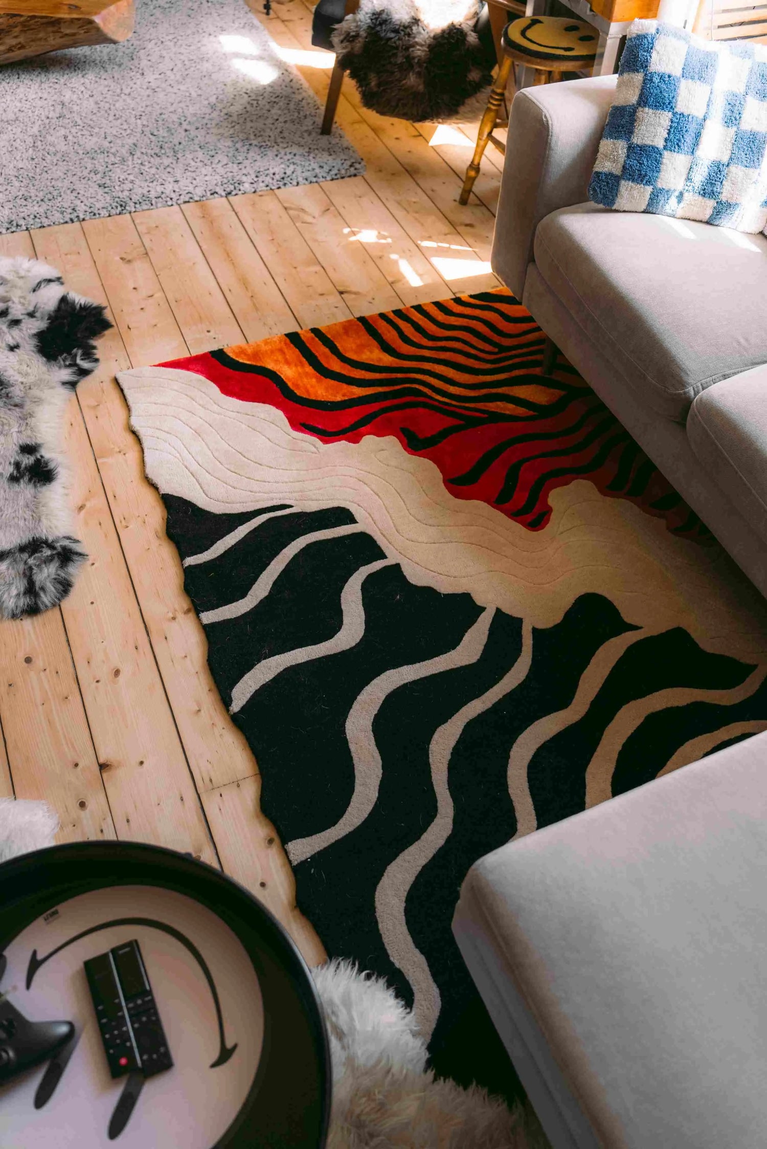 A vibrant, curved line hand tufted area rug adds a modern touch to a cozy living room. This contemporary wool rug features bold colors and abstract patterns, perfect for enhancing any living room area.