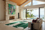 Modern living room with stone fireplace, green rug, and ocean view.