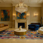 A luxurious living room featuring an eye-catching hand-knotted area rug with vibrant abstract patterns. The contemporary rug adds a splash of color to the elegant setting, complemented by a crystal chandelier and modern art pieces. This large living room rug, reminiscent of Persian rugs, beautifully ties the space together.