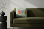 An olive green sofa in a modern room setting, featuring a square throw pillow with a colorful embroidered tiger design on a sage green background.