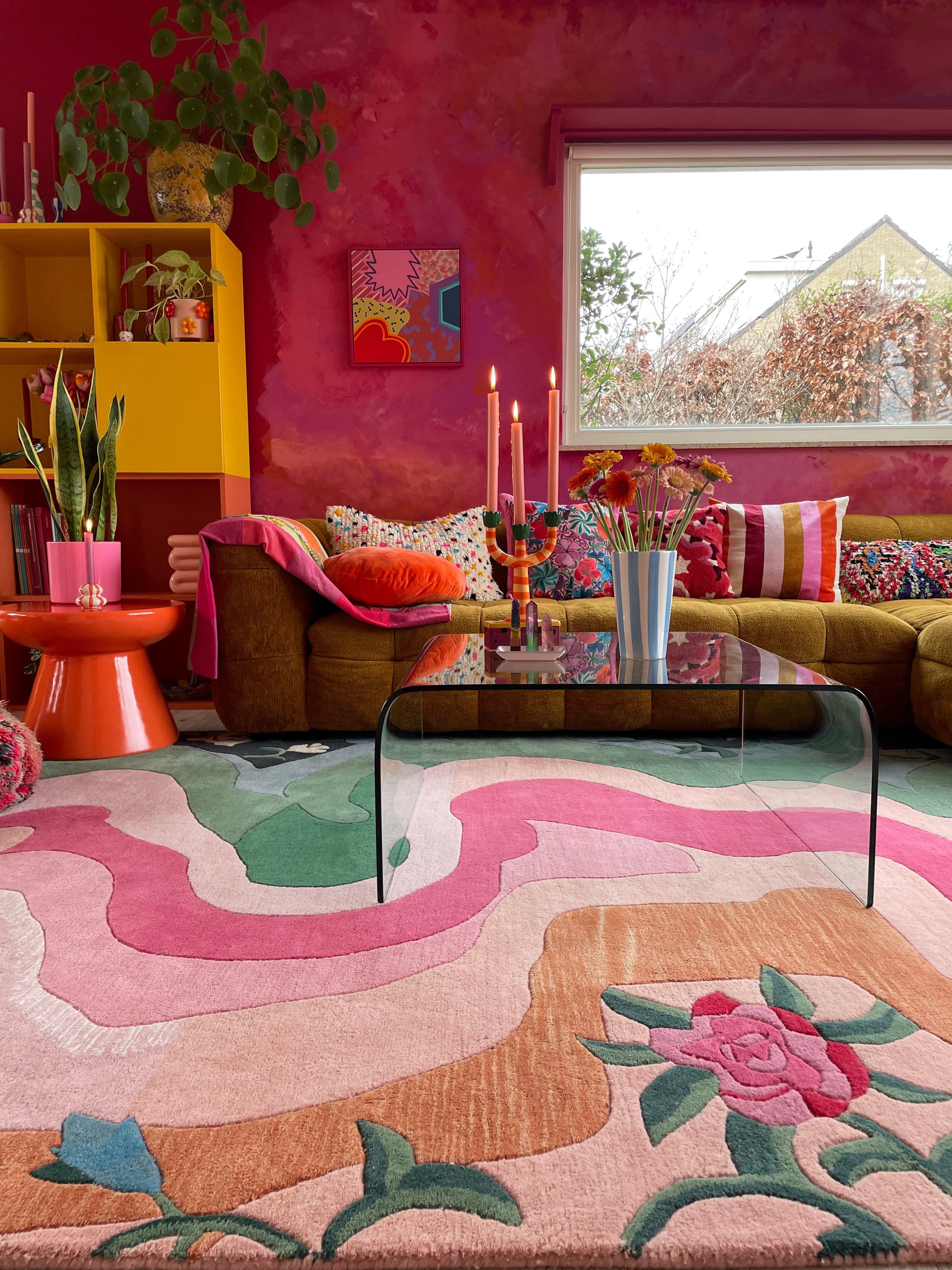 Colorful room with pink walls, floral rug, and various decor elements.