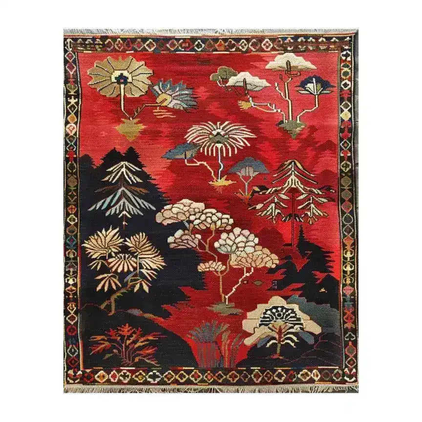 A vibrant, hand-knotted wool area rug showcasing a forest fantasy theme with intricate floral and tree patterns. The large area rug features rich red, blue, and cream colors, making it an ideal choice for a living room centerpiece. This Persian-inspired floral rug combines elegance with a natural touch, perfect for enhancing any space.