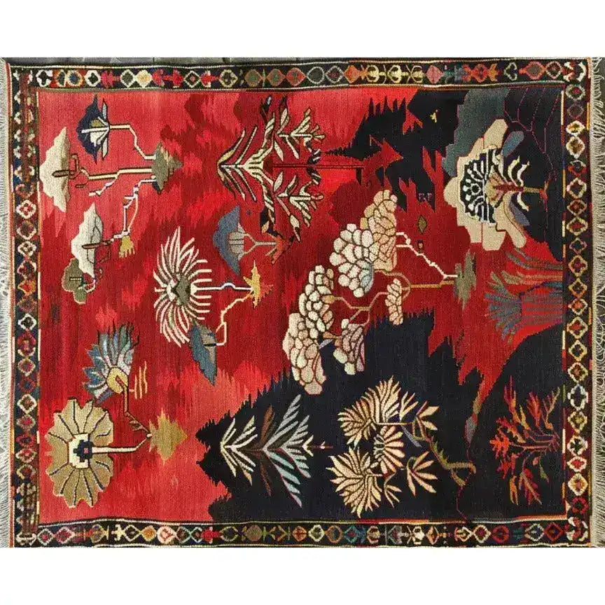 This vibrant Forest Fantasy Medium Hand Knotted Wool Rug, perfect for a living room, showcases a rich array of floral patterns in deep reds and contrasting dark hues. This large area rug, inspired by traditional Persian designs, highlights the intricate craftsmanship of a luxurious wool rug.