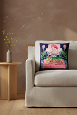 A square decorative throw pillow with a colorful tropical flamingo and tiger print, styled on a cream-colored fabric slipcovered sofa against a textured beige wall and light wood floor.