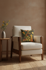 A cream upholstered armchair with a dark floral accent pillow, set in a warm, minimalist room with a textured brown wall, light wood floor, and a small side table with yellow flowers.