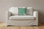 A cream-colored slipcovered loveseat sofa with a decorative throw pillow featuring a green background, pink ducks, and pink flowers, set against a textured beige wall and light wood flooring.