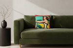 A square throw pillow featuring a retro-style illustration of a woman in a yellow dress leaning against a teal and red vehicle, styled on a white slipcovered sofa against a textured beige wall.