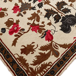 Close-up of the Golden Glory Square Hand Tufted Wool Rug showcasing its intricate floral design with vibrant red, brown, and black patterns on a cream background. This elegant square area rug is perfect for adding a touch of sophistication to a bedroom or large living room, enhancing the space with its luxurious wool texture.