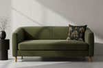 A square throw pillow with a black background and gold palm tree pattern, styled on a white sofa against a beige wall.