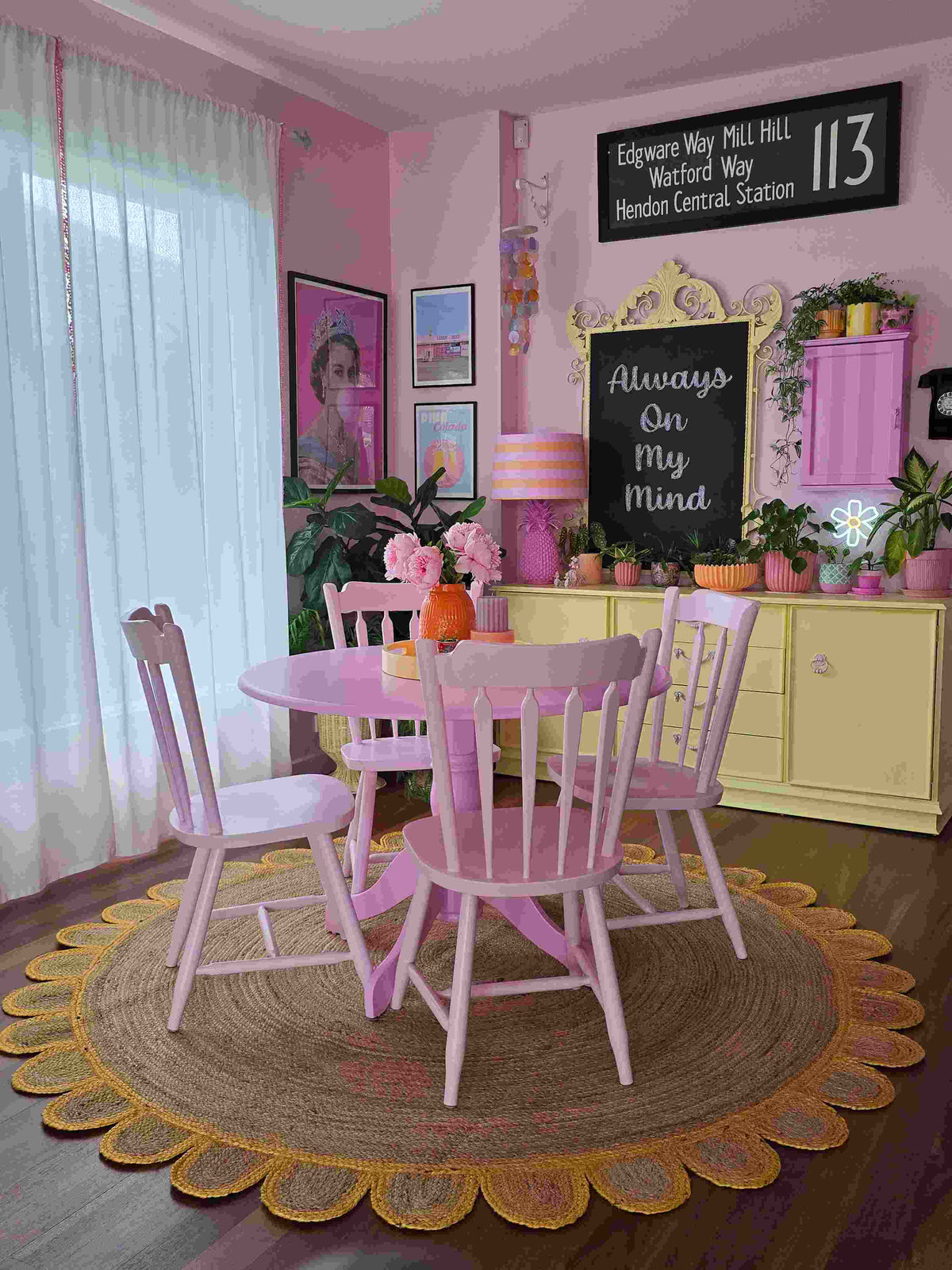 A vibrant living room featuring a handmade yellow scalloped round jute rug as the centerpiece. The natural texture of the area rug complements the pink dining set, creating a cozy and inviting atmosphere. Ideal for adding warmth to any living room, this round rug showcases a perfect blend of style and sustainability.