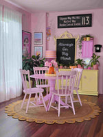 A cozy living room featuring a handmade yellow scalloped round jute area rug, perfectly complementing a pastel pink dining set. This area rug adds warmth and texture to the space, ideal for those seeking stylish area rugs for living room decor.