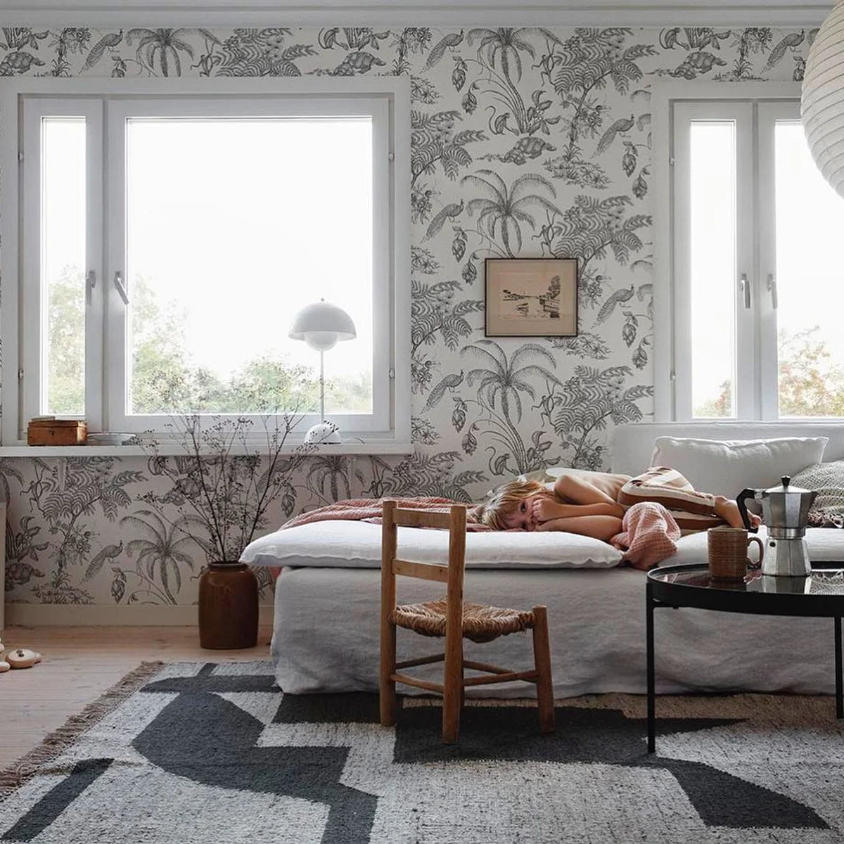 Cozy living room with floral wallpaper, a sofa, and a rug.