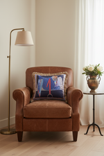 An olive green velvet sofa in a modern living room setting, styled with a decorative throw pillow and a small wooden side table with dried flowers.