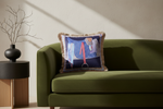 An olive green velvet sofa in a modern living room setting, styled with a decorative throw pillow and a small wooden side table holding a vase with dried branches.