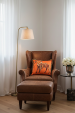 A white armchair with a light gray upholstered seat, styled in a room with a gray paneled wall, a wooden floor, a floor lamp, and a side table. The chair features a decorative green throw pillow with a gold horse design.