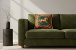 A white armchair with a light gray upholstered seat, styled in a room with a gray paneled wall, a wooden floor, a floor lamp, and a side table. The chair features a decorative green throw pillow with a gold horse design.