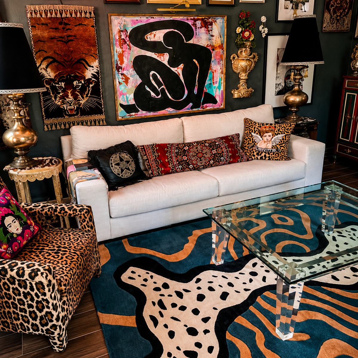 A styled living room featuring a white sofa with patterned throw pillows, a leopard-print armchair, a blue and tan abstract-patterned rug, and multiple framed artworks on a dark wall.