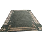 Green rug with beige border design on a white background