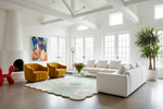 Modern living room with white walls, contemporary scallop rug, large windows, and colorful decor.